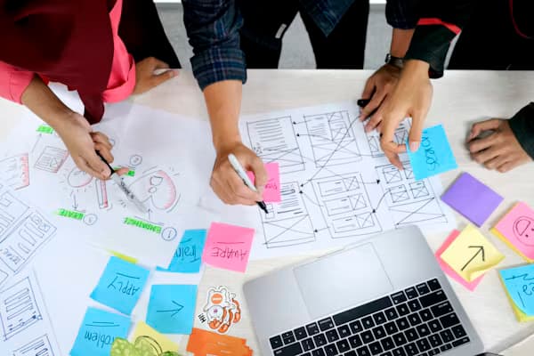 Team sketching curriculum wireframes with sticky notes