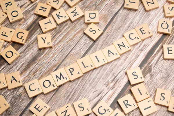 Wooden letter tiles spelling compliance