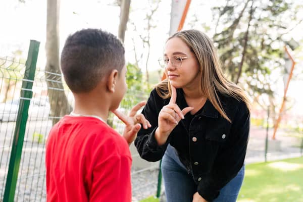 Interpreter using sign language with a young student outdoors
